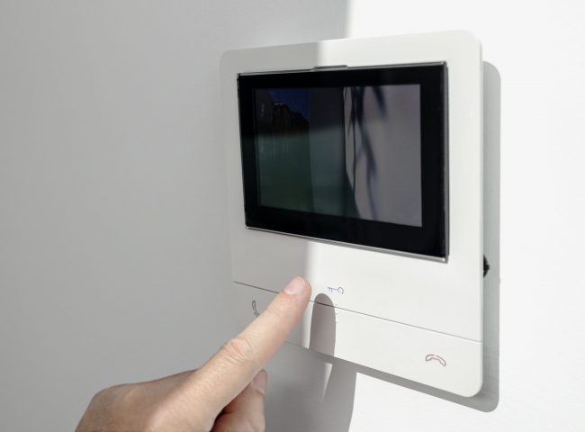 Intercom in home interior and a hand ready to open the door button. House Security system. Copy space